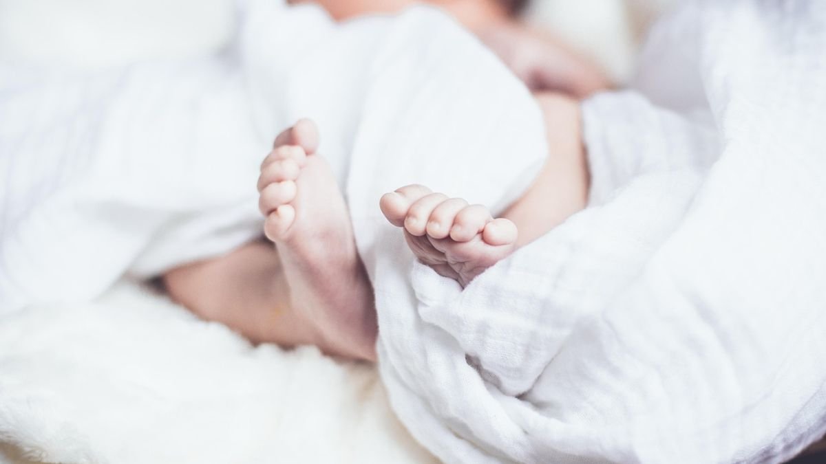 bebe deitado em cama com cobertor branco
