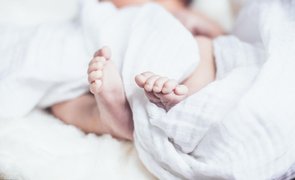 bebe deitado em cama com cobertor branco